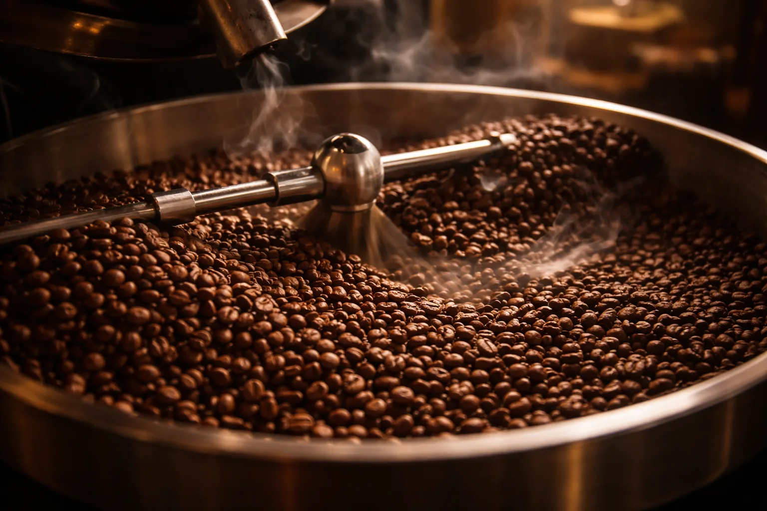 Endüstriyel tamburlu kavurucuda kızıl kahve çekirdekleri, sıcak ışık ve yükselen duman.