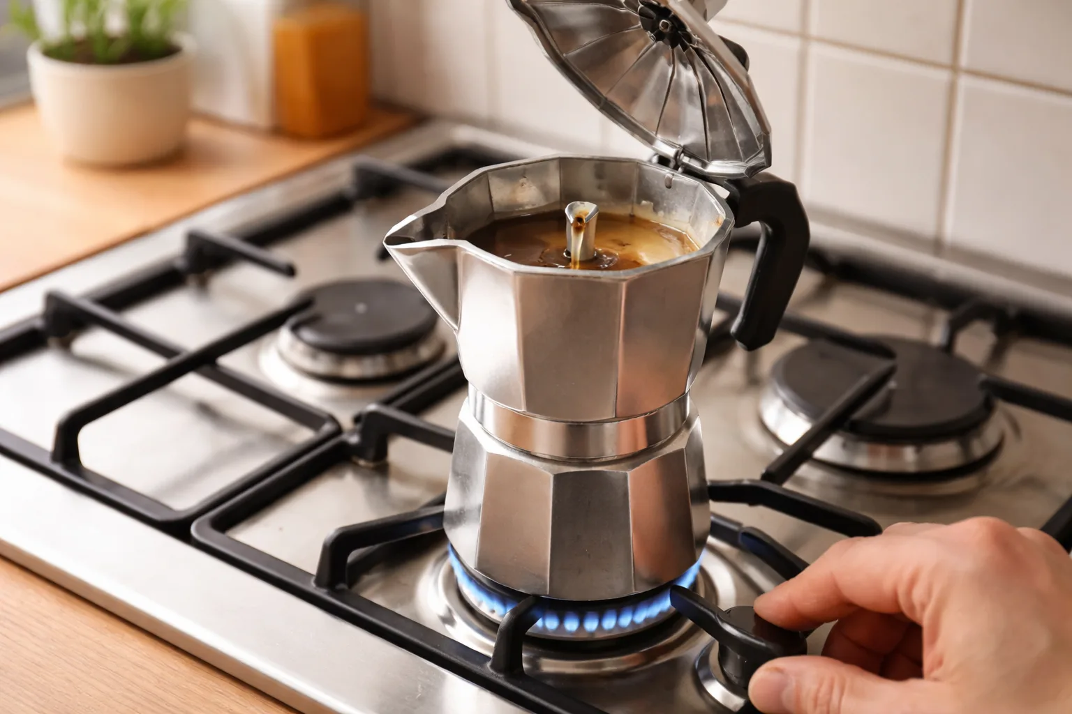 Kapak açık üst haznede kahve rengi koyudan orta tona dönerken, el ocağın düğmesini kısıyor, ince akış ve düşük alev